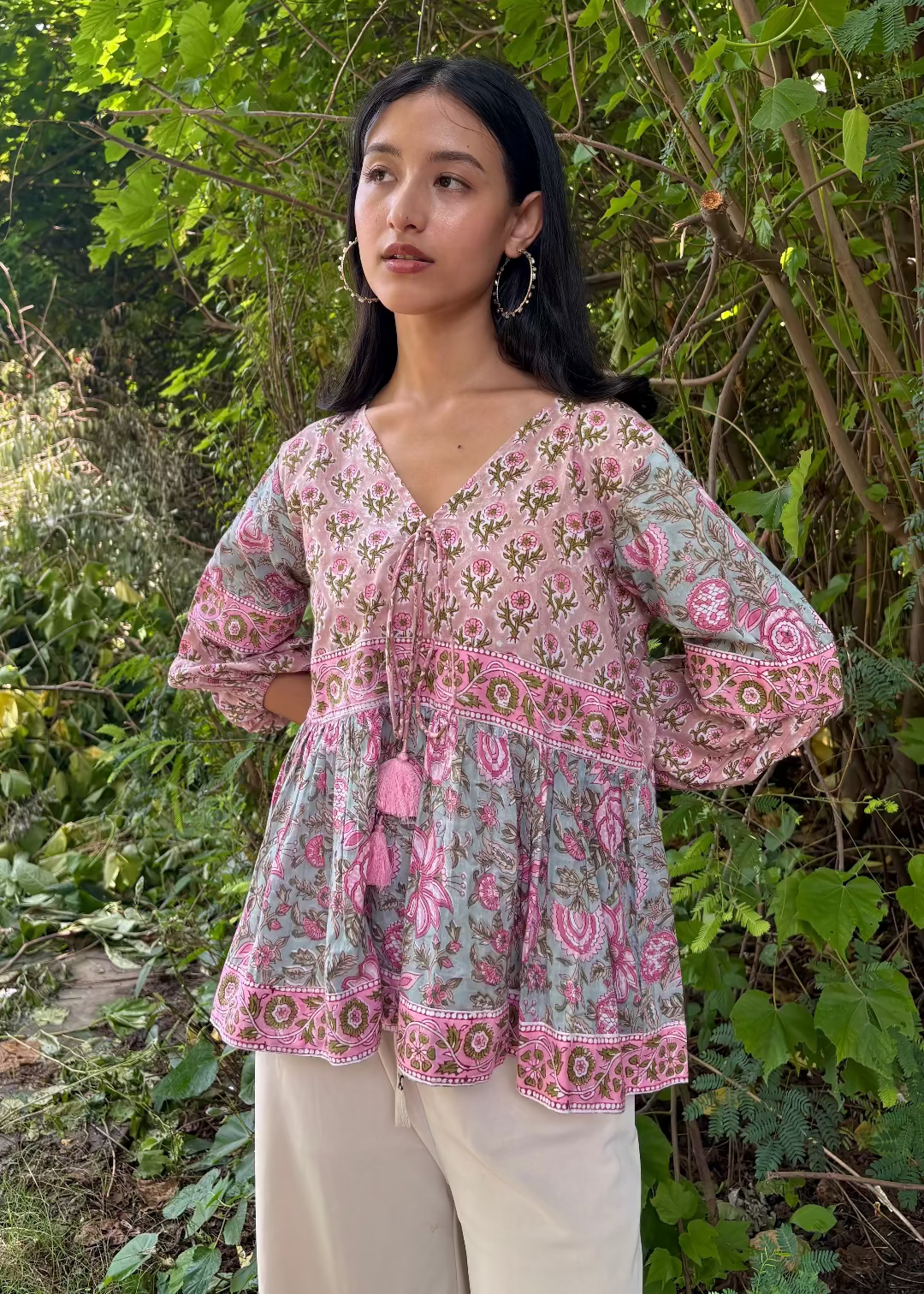 Woman wearing a Meher Peplum floral Printed Top That Romeo standing in a garden
