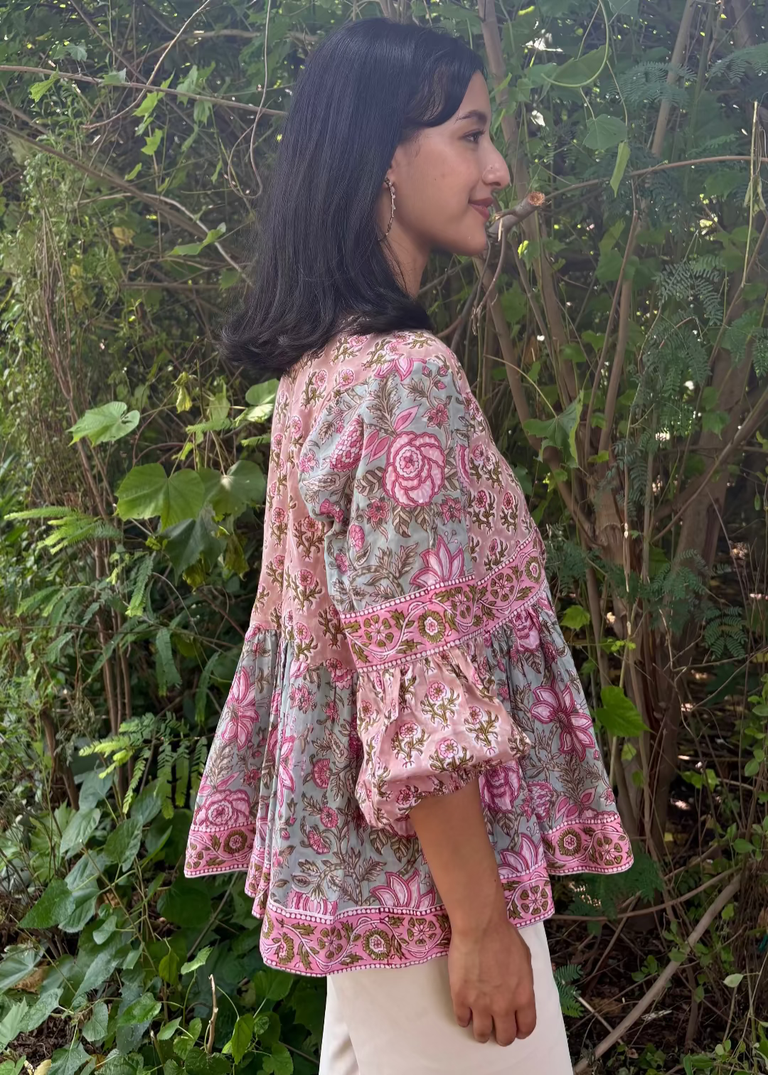 Woman wearing a Meher Peplum floral Printed Top That Romeo standing in a garden