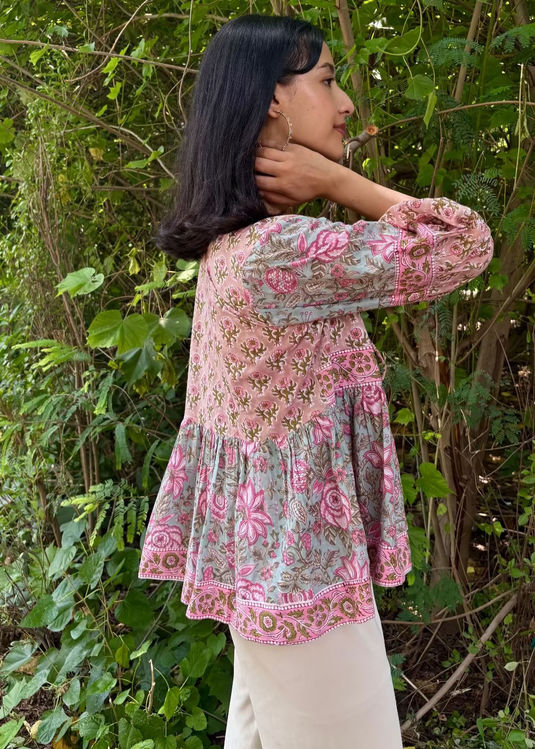 Woman wearing a Meher Peplum floral Printed Top That Romeo standing in a garden