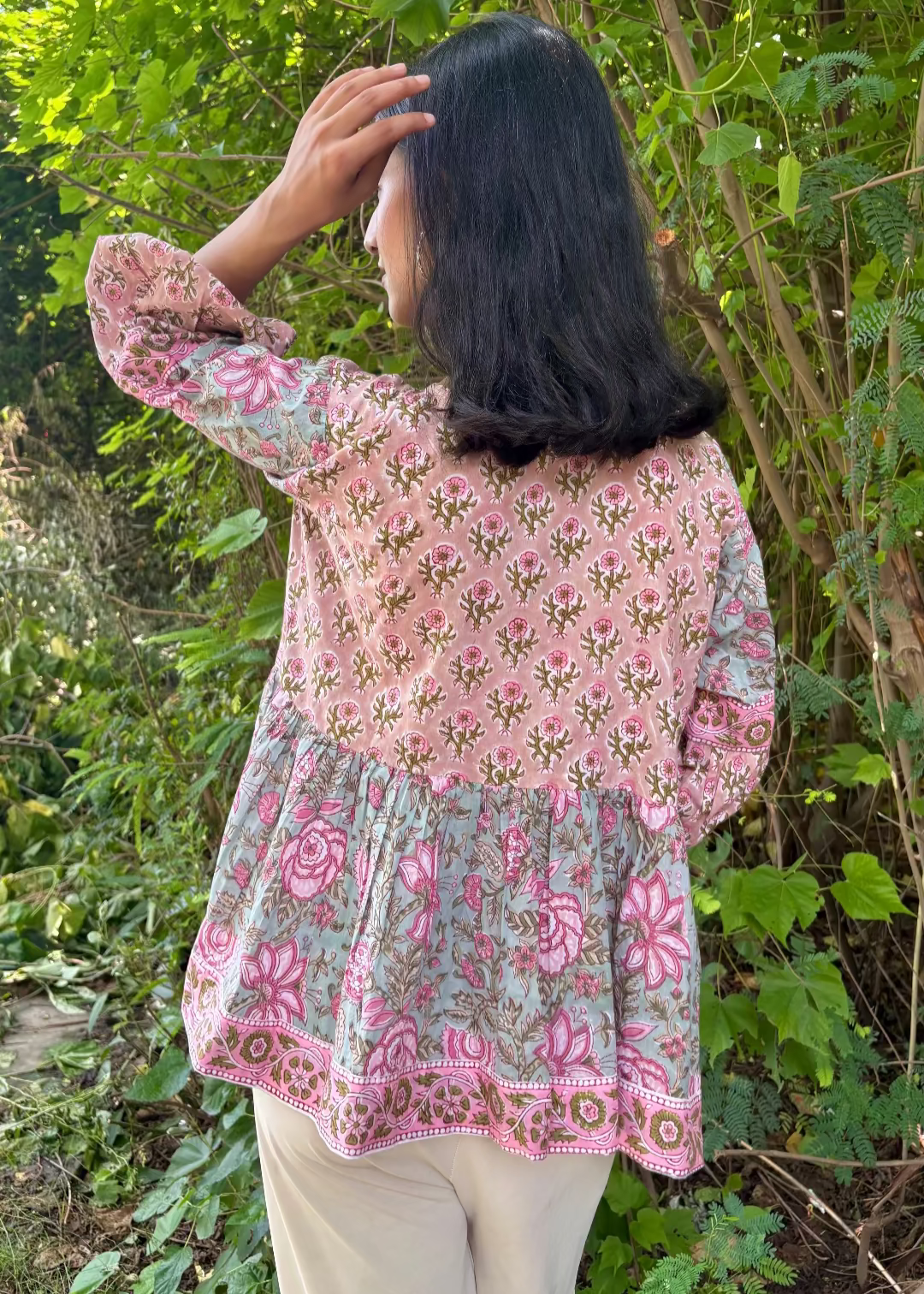 Woman wearing a Meher Peplum floral Printed Top That Romeo standing in a garden