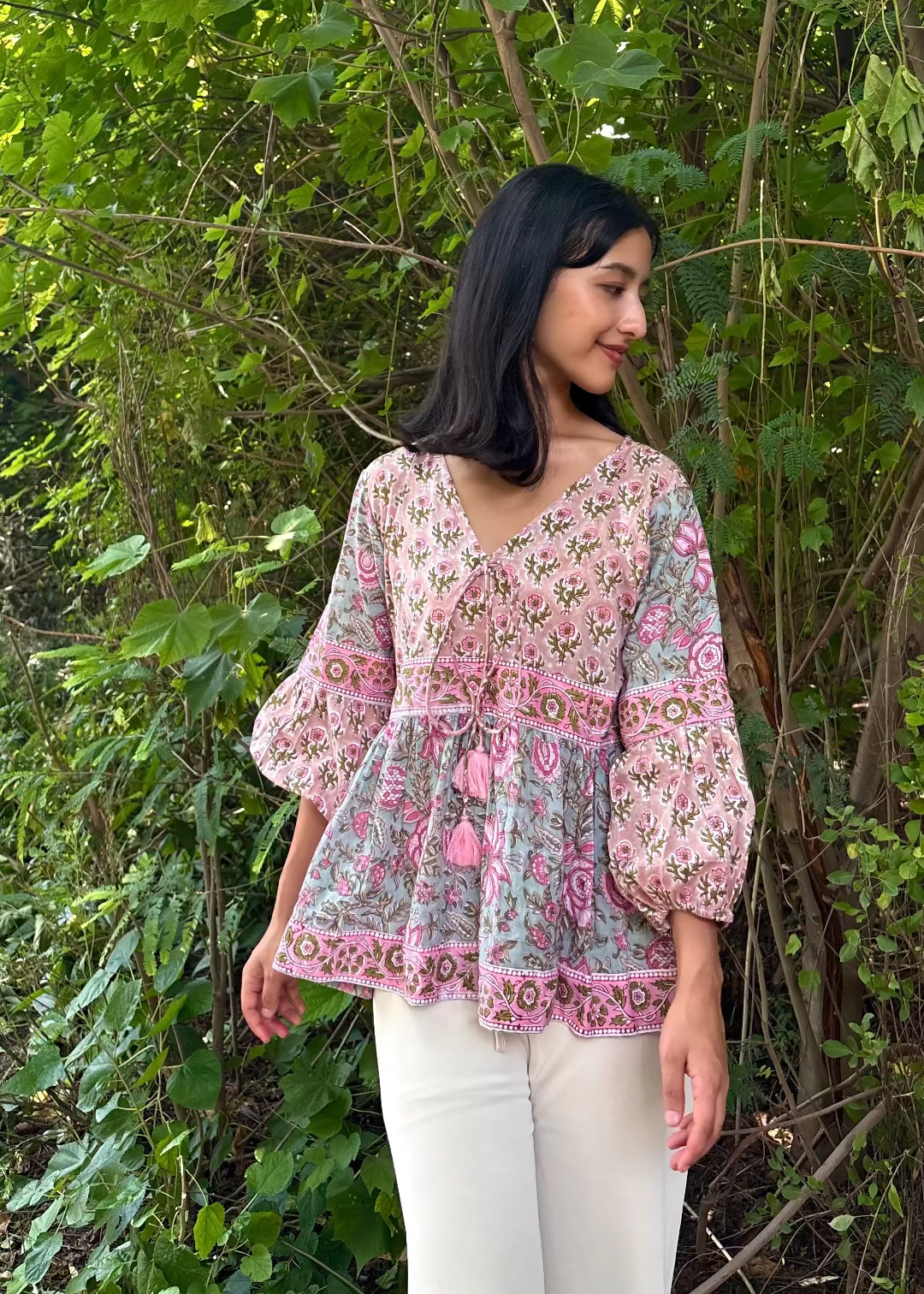 Woman wearing a Meher Peplum floral Printed Top That Romeo standing in a garden