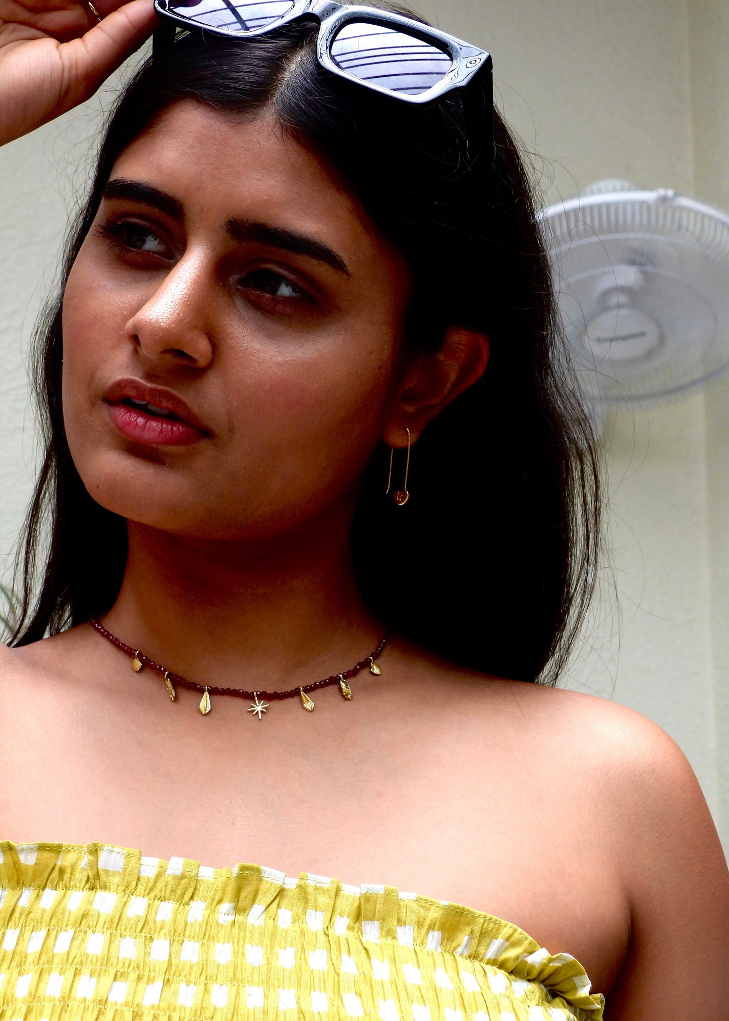 Woman wearing a delicate Easy breezy That Romeo necklace with small gold beads against a neutral background