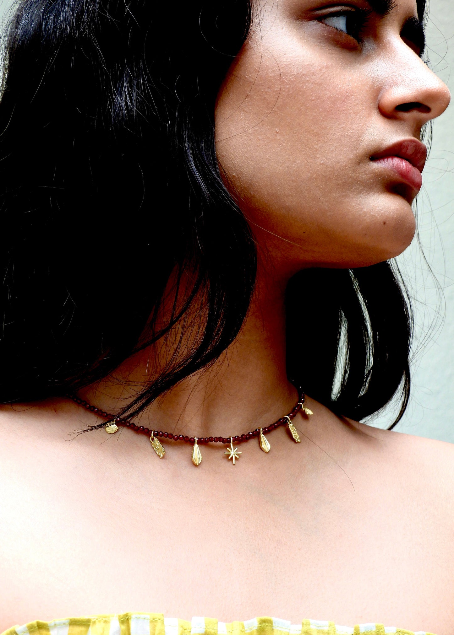 Woman wearing a delicate Easy breezy That Romeo necklace with small gold beads against a neutral background