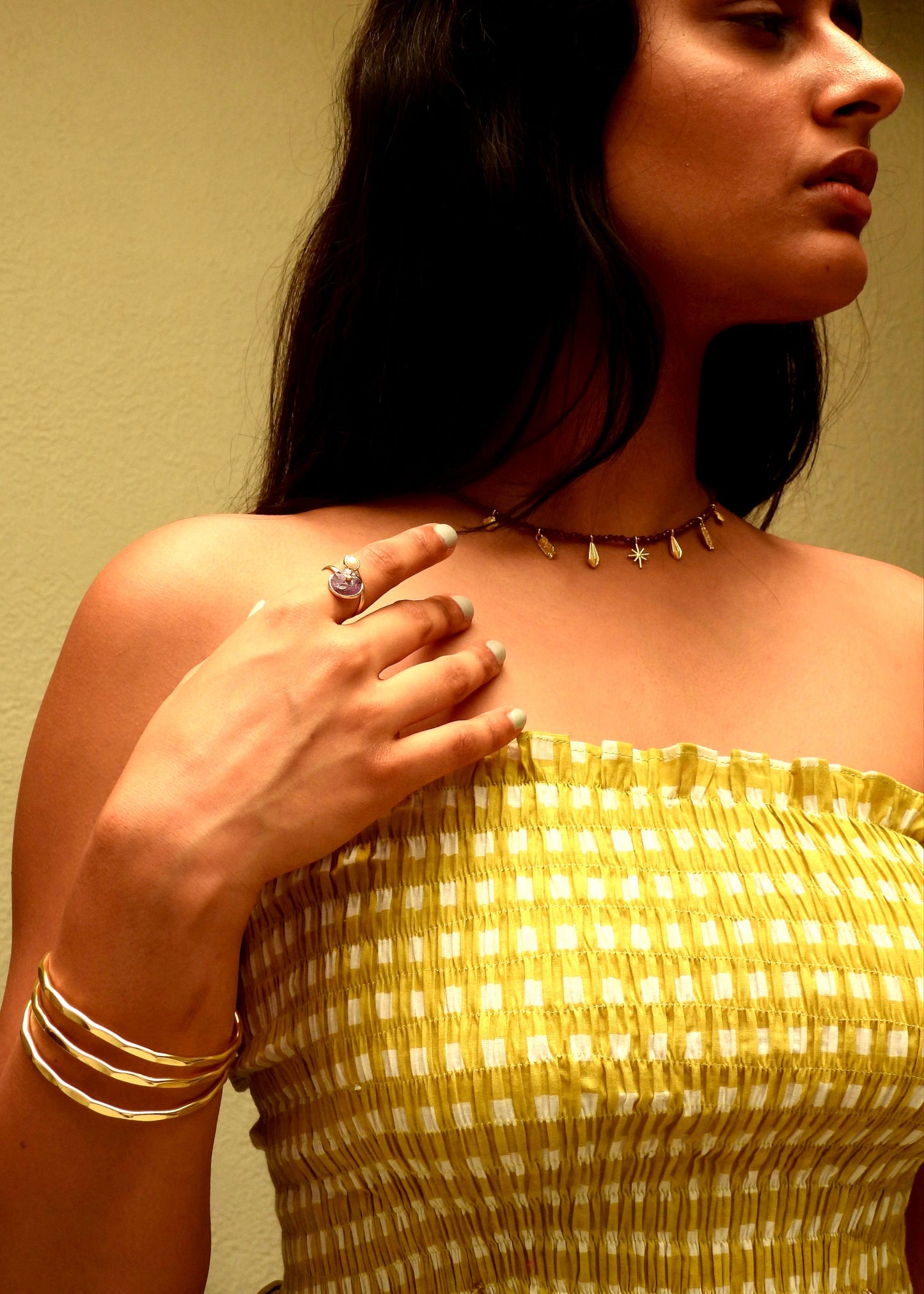 Woman wearing a delicate Easy breezy That Romeo necklace with small gold beads against a neutral background
