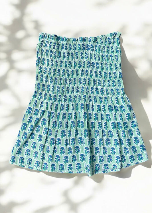 A mint and blue strapless smocked top in cotton with leafy handblock prints, laid flat in soft natural light by That Romeo