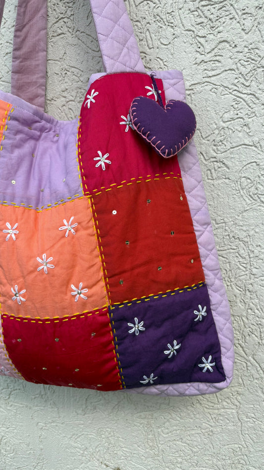 That Romeo handmade tote in lilac, peach, red, and violet with floral Kantha embroidery and a heart charm — quilted, upcycled, and artisan-crafted