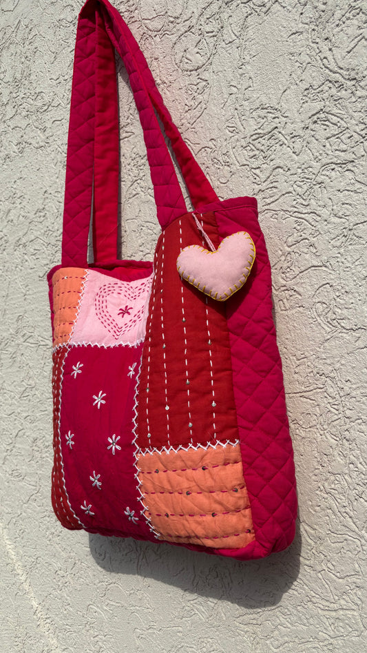 That Romeo handmade quilted tote in blush, rust, and red tones with Kantha heart embroidery, patchwork design, and heart charm — sustainable and artisanal