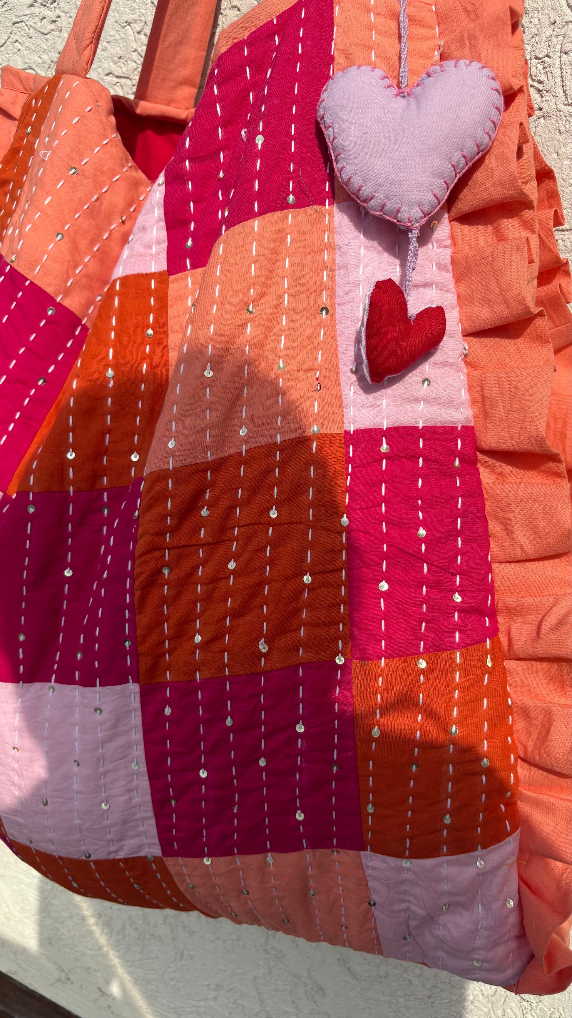 Handmade zero-waste quilted tote bag with pink and orange patchwork, Kantha embroidery, and heart charm – sustainable fashion accessory
