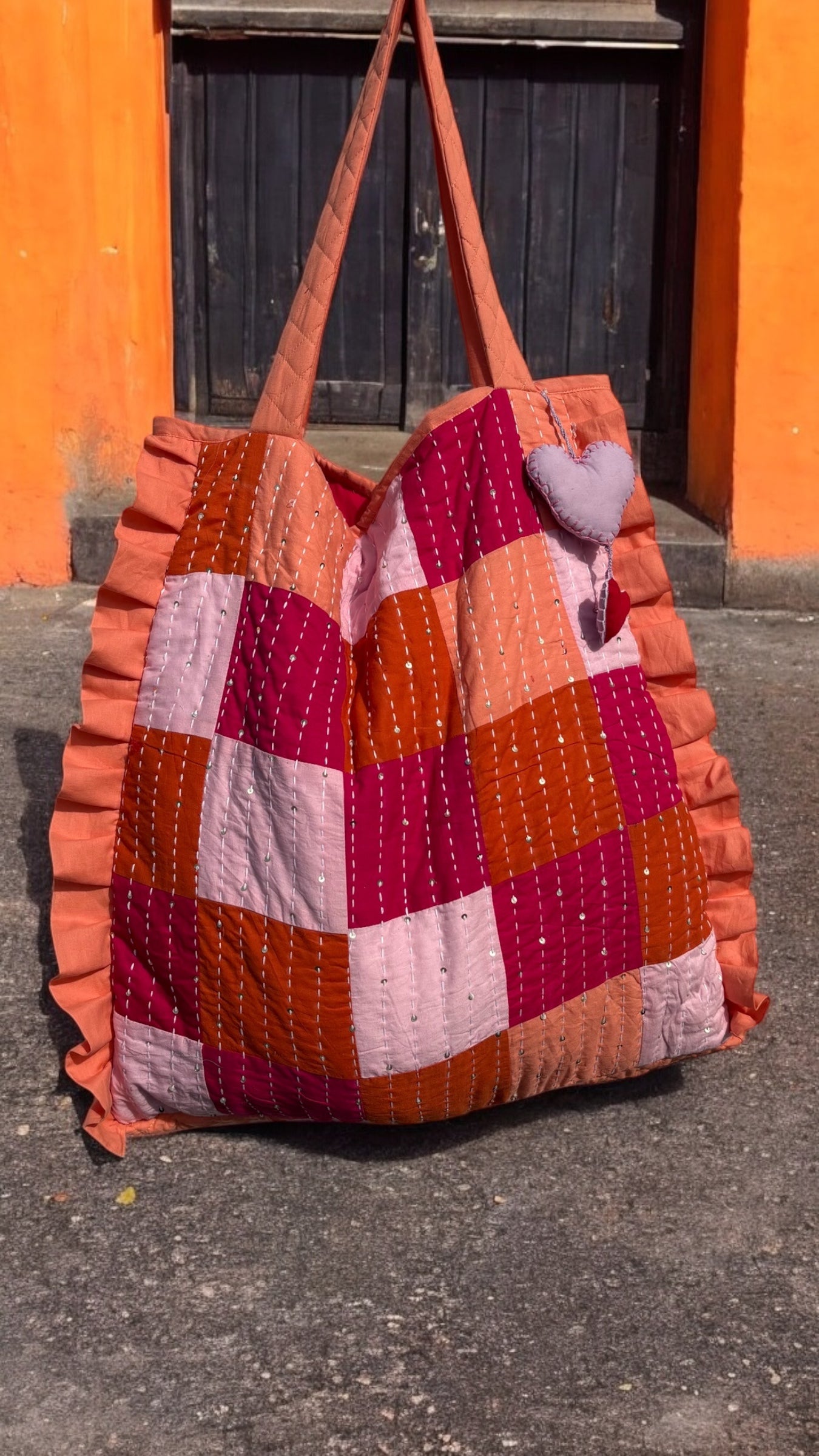 Handmade zero-waste quilted tote bag with pink and orange patchwork, Kantha embroidery, and heart charm – sustainable fashion accessory