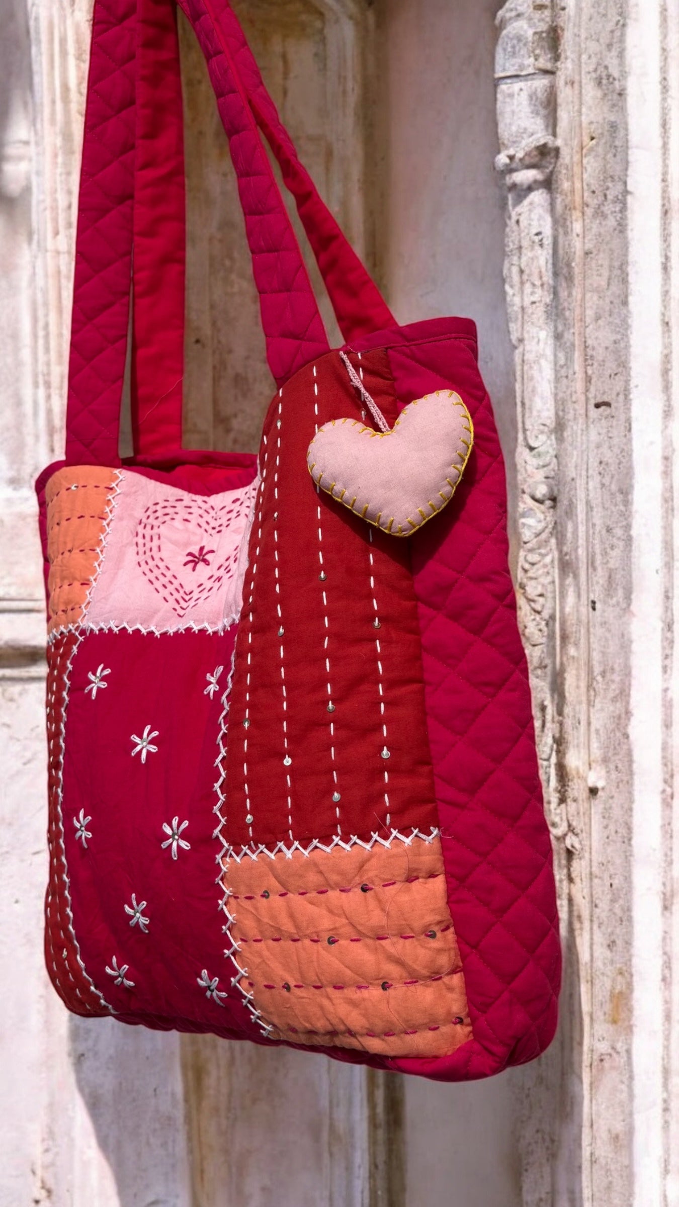 That Romeo handmade quilted tote in blush, rust, and red tones with Kantha heart embroidery, patchwork design, and heart charm — sustainable and artisanal