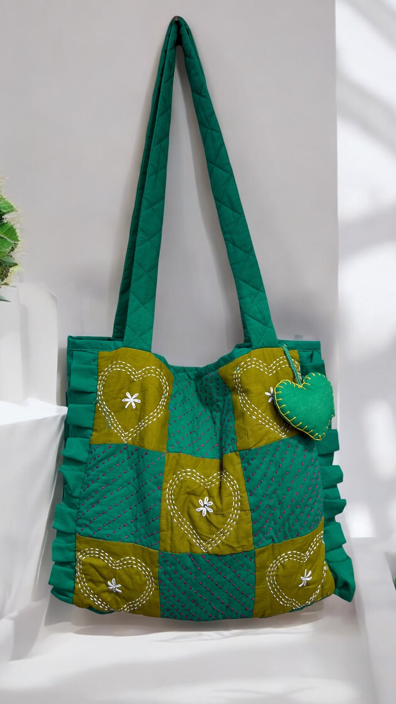 That Romeo quilted green tote with moss heart-embroidered patchwork, Kantha stitches, ruffled sides, and a plush charm — handmade and eco-friendly