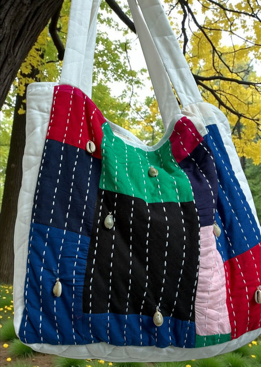 Handcrafted patchwork quilted tote bag by that romeo in multicolor cotton with kantha stitches and cowrie shells.