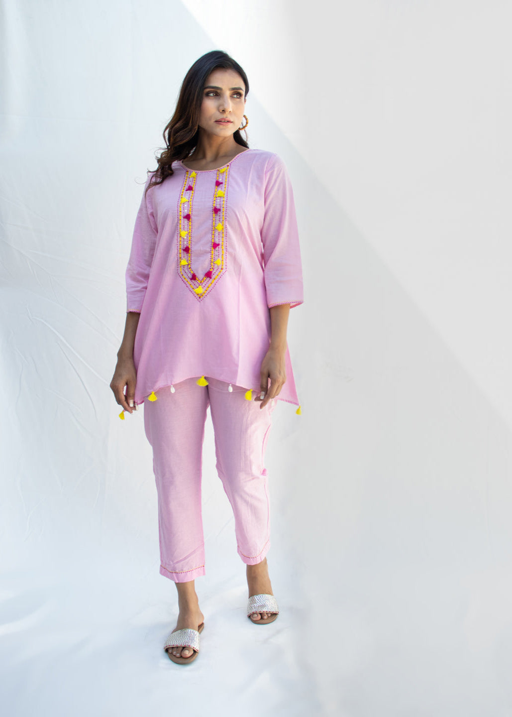 Model wearing the MANJU light pink cotton co-ord set featuring Katha and Dori embroidery, yellow tassels, and kodi detailing on the hem – a breezy handcrafted look from That Romeo’s PARDESI Collection.