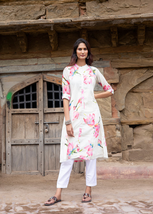 Model in ivory chanderi silk kurta with blooming pink lotus print and white trousers, standing against a rustic heritage wall.