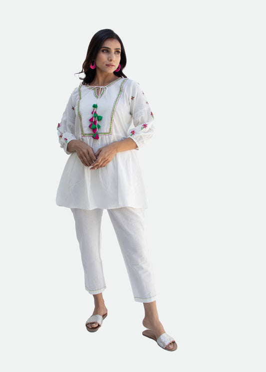 Model wearing the ASTA white cotton co-ord set with colorful tassels and intricate Katha embroidery on the gathered top – a sustainable style piece from That Romeo’s PARDESI Collection.