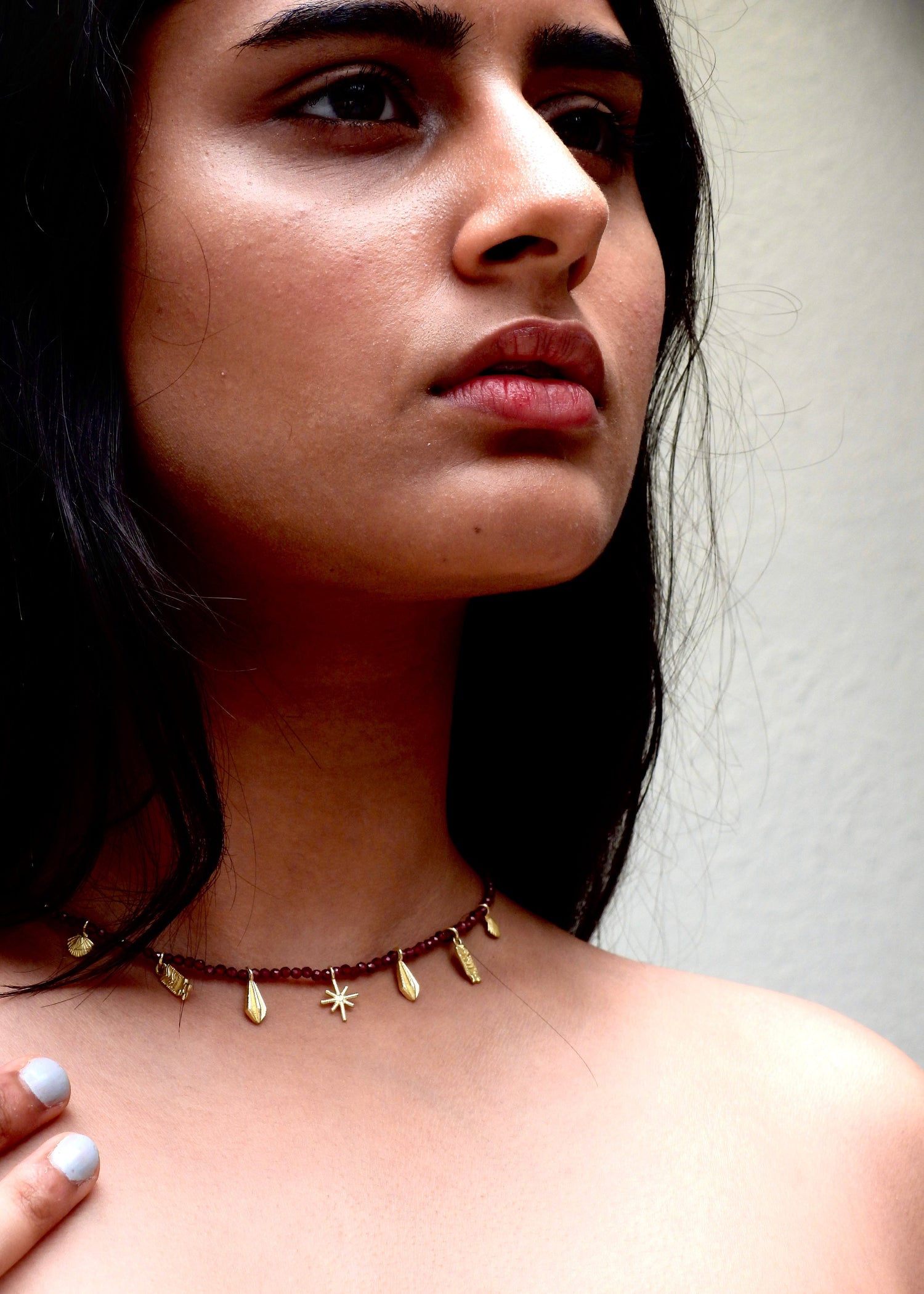 Woman wearing a delicate Easy breezy That Romeo necklace with small gold beads against a neutral background