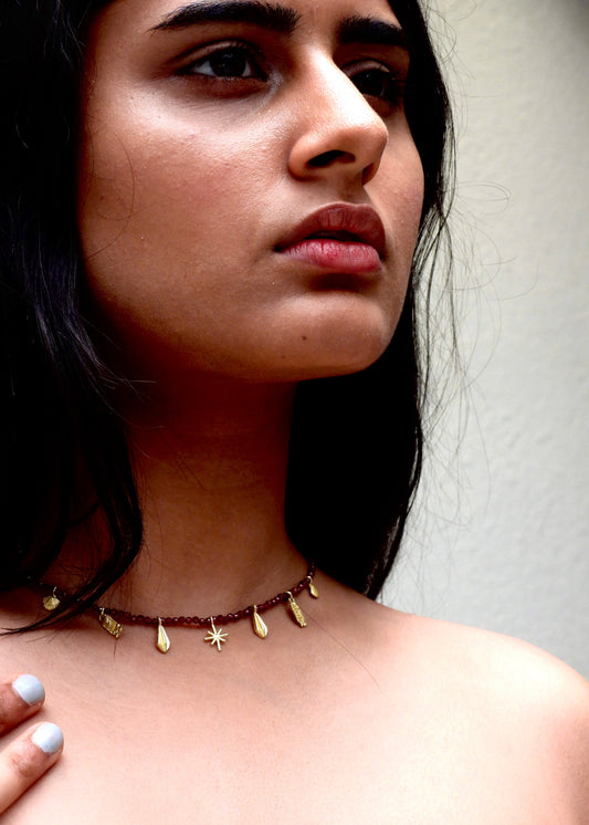 Woman wearing a delicate Easy breezy That Romeo necklace with small gold beads against a neutral background