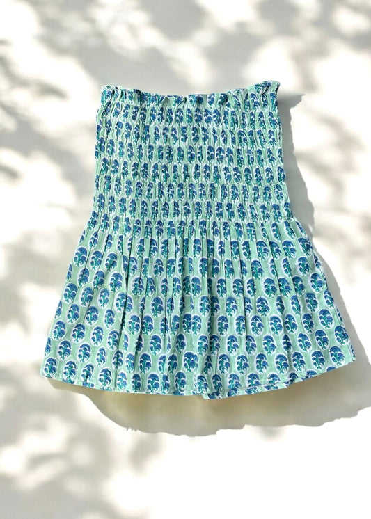 A mint and blue strapless smocked top in cotton with leafy handblock prints, laid flat in soft natural light by That Romeo