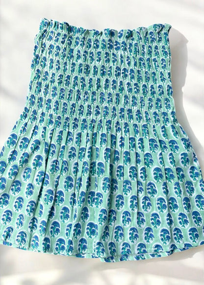 A mint and blue strapless smocked top in cotton with leafy handblock prints, laid flat in soft natural light by That Romeo