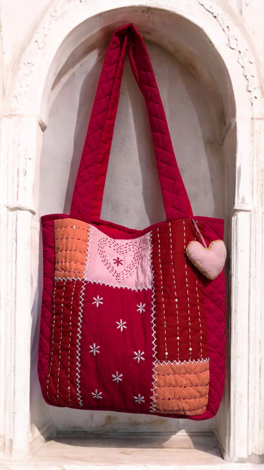 That Romeo handmade quilted tote in blush, rust, and red tones with Kantha heart embroidery, patchwork design, and heart charm — sustainable and artisanal