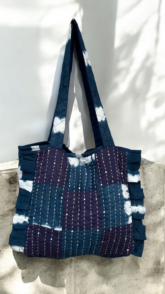 Handmade quilted tote in shibori and deep indigo patchwork with vertical Kantha stitches and ruffle sides — artisan-crafted by That Romeo using upcycled cotton