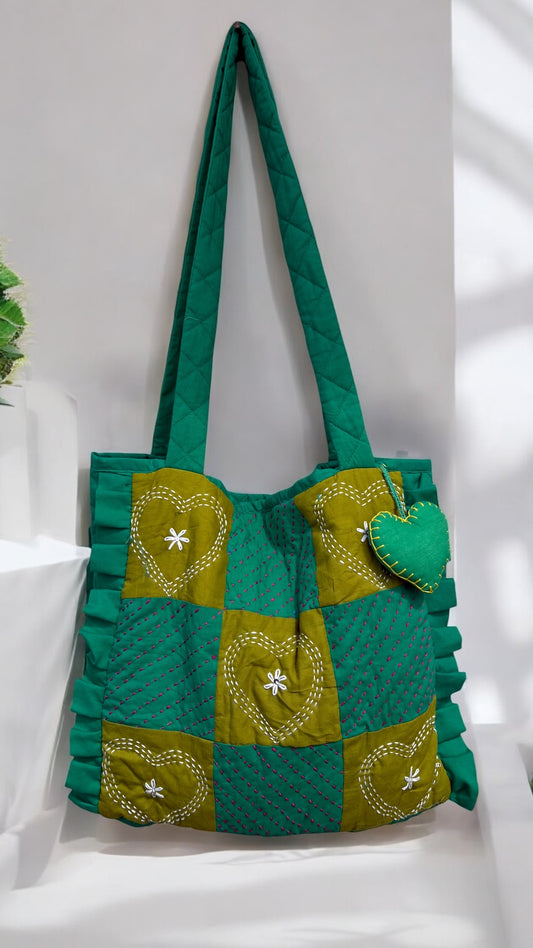 That Romeo quilted green tote with moss heart-embroidered patchwork, Kantha stitches, ruffled sides, and a plush charm — handmade and eco-friendly
