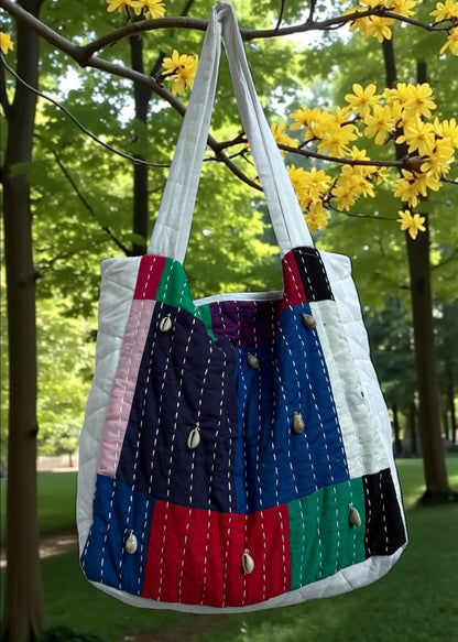 Handcrafted patchwork quilted tote bag by that romeo in multicolor cotton with kantha stitches and cowrie shells.