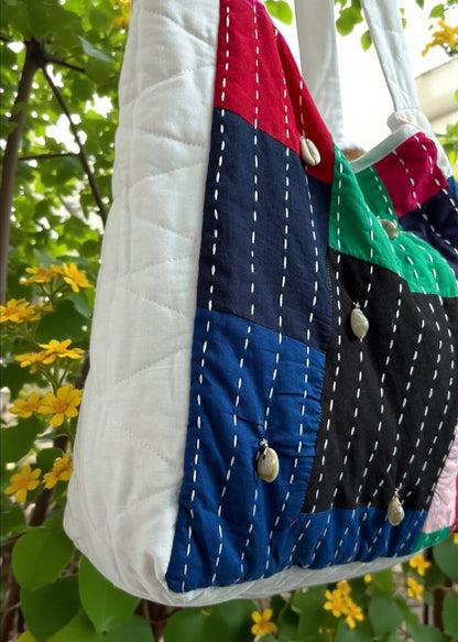 Handcrafted patchwork quilted tote bag by that romeo in multicolor cotton with kantha stitches and cowrie shells.