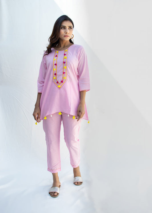 Model wearing the MANJU light pink cotton co-ord set featuring Katha and Dori embroidery, yellow tassels, and kodi detailing on the hem – a breezy handcrafted look from That Romeo’s PARDESI Collection.