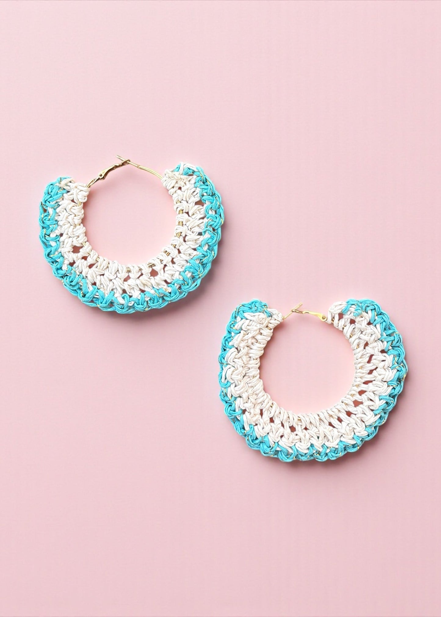 Aqua blue and white crochet hoop earrings by ThatRomeo on a soft pink background.