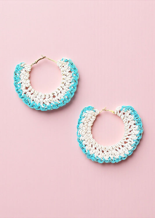 Aqua blue and white crochet hoop earrings by ThatRomeo on a soft pink background.