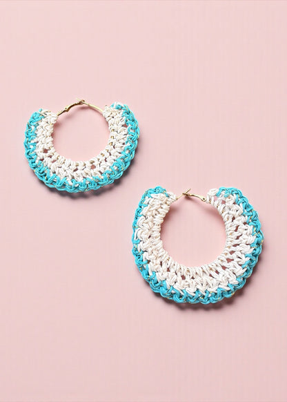 Aqua blue and white crochet hoop earrings by ThatRomeo on a soft pink background.