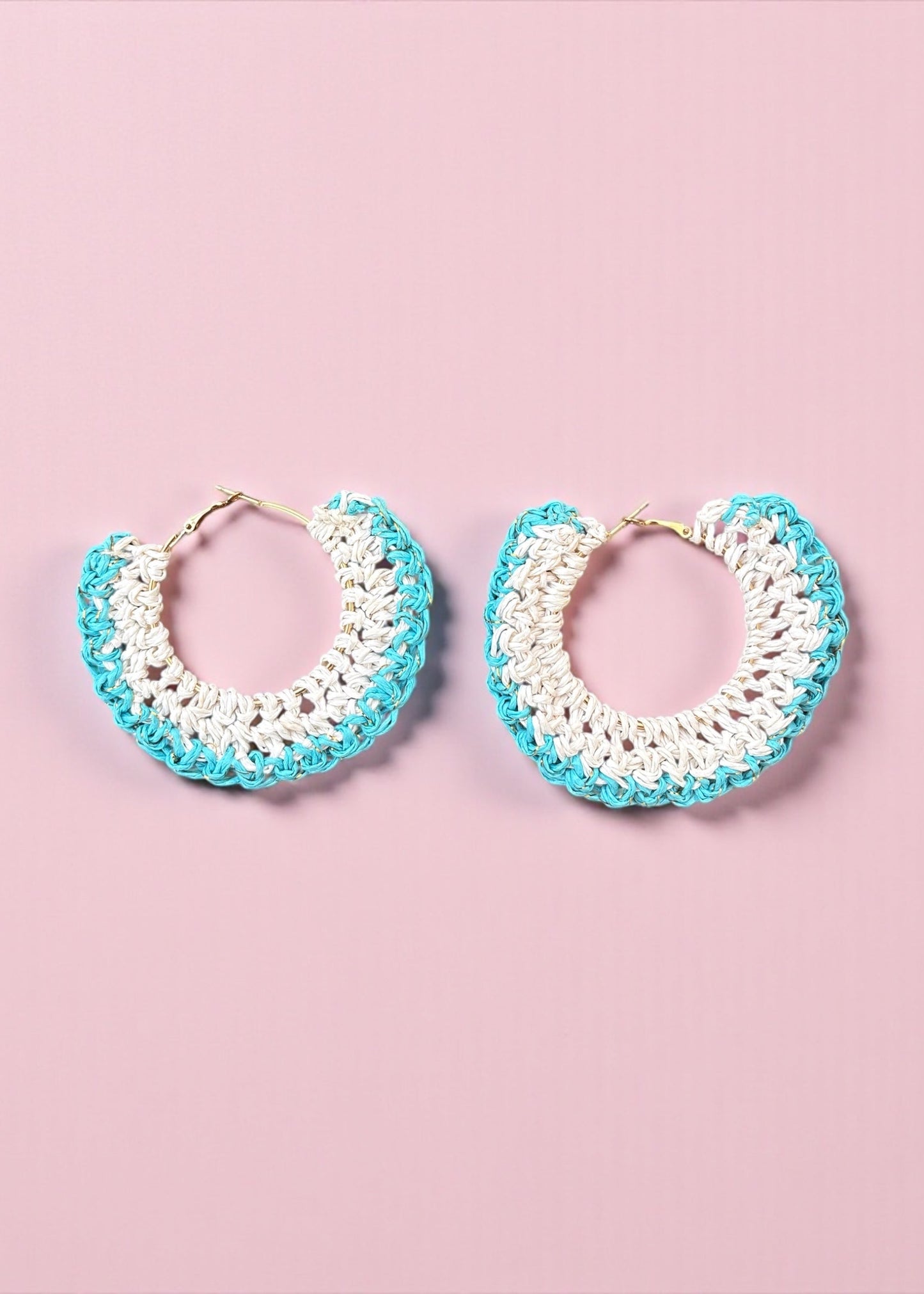 Aqua blue and white crochet hoop earrings by ThatRomeo on a soft pink background.