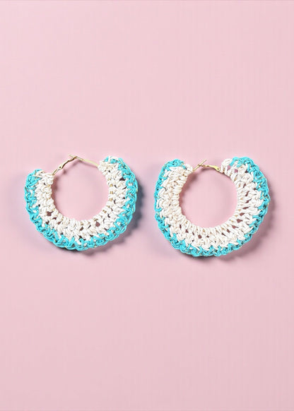Aqua blue and white crochet hoop earrings by ThatRomeo on a soft pink background.