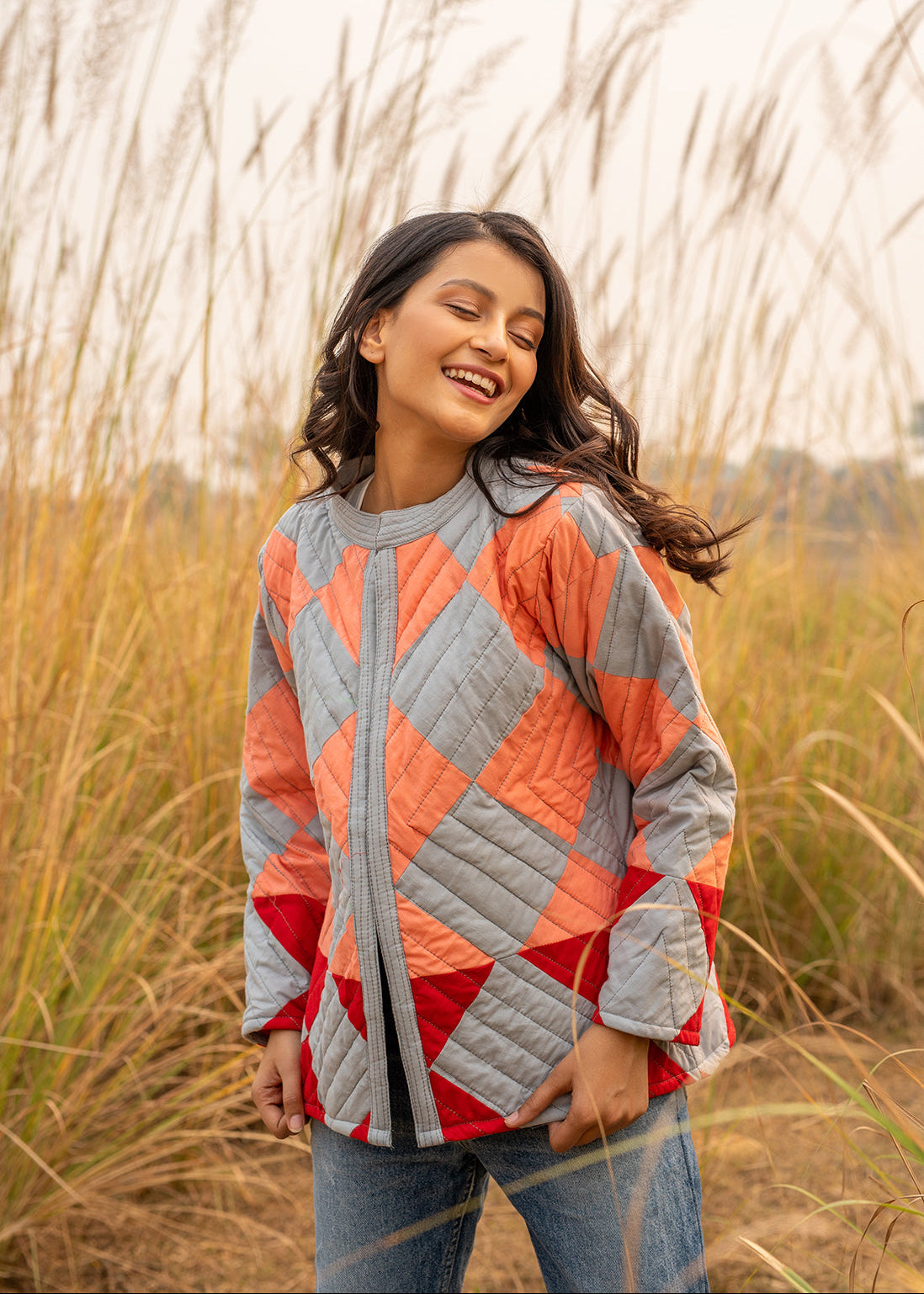 Model wearing ThatRomeo’s Boxy Patchwork Jacket — geometric quilted cotton jacket in coral, grey, and red tones.