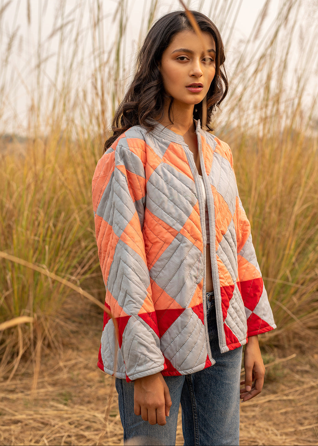 Model wearing ThatRomeo’s Boxy Patchwork Jacket — geometric quilted cotton jacket in coral, grey, and red tones.