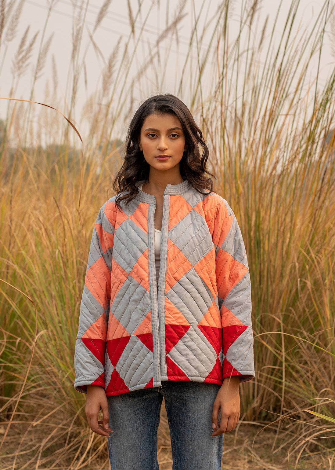 Model wearing ThatRomeo’s Boxy Patchwork Jacket — geometric quilted cotton jacket in coral, grey, and red tones.