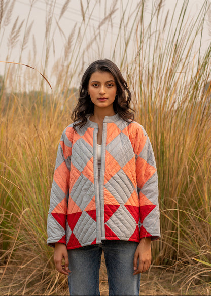 Model wearing ThatRomeo’s Boxy Patchwork Jacket — geometric quilted cotton jacket in coral, grey, and red tones.