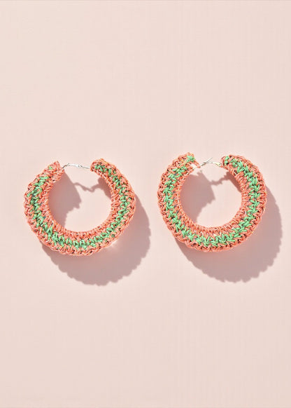 Coral and green crochet hoop earrings by ThatRomeo on a soft pink background.