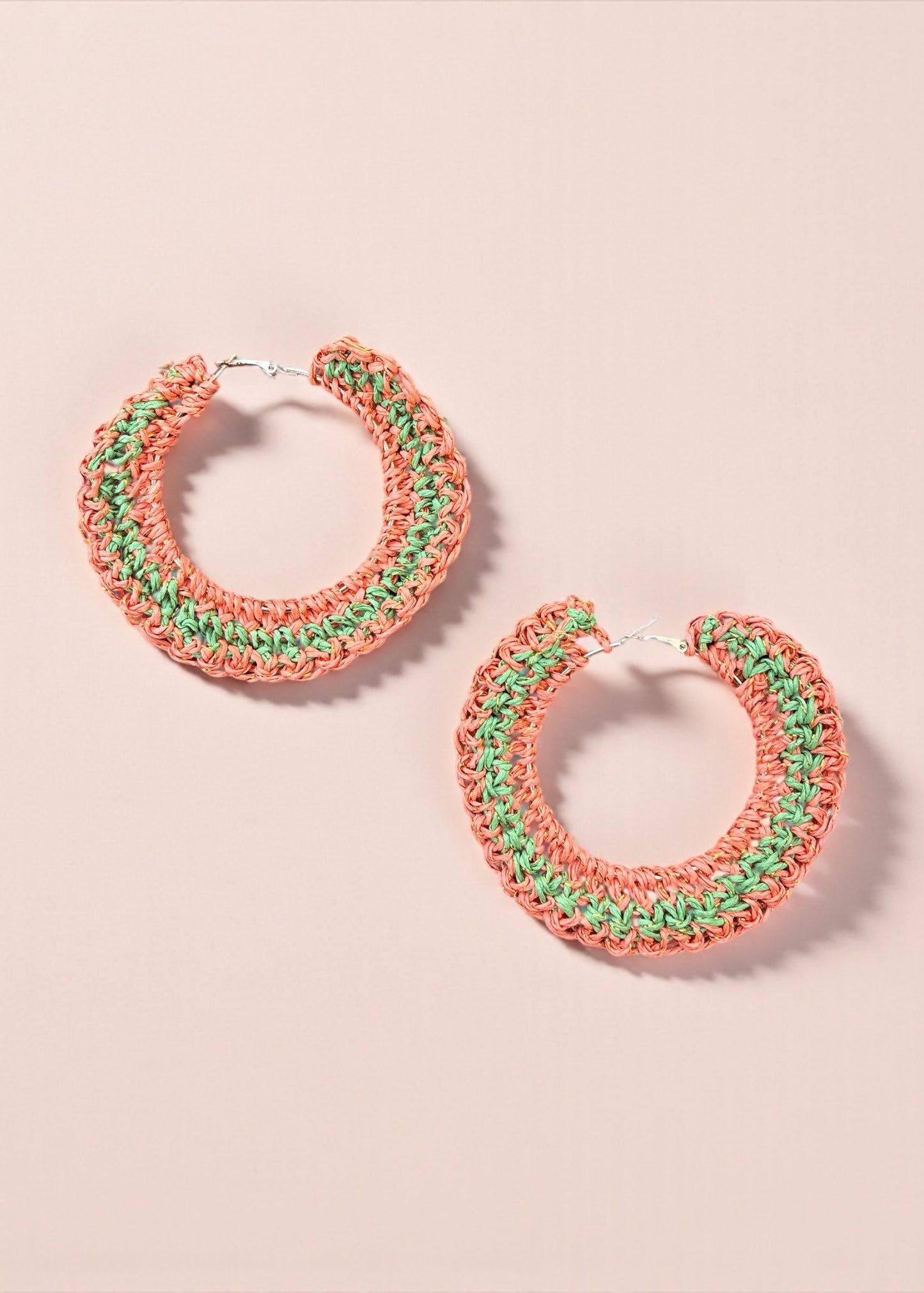 Coral and green crochet hoop earrings by ThatRomeo on a soft pink background.