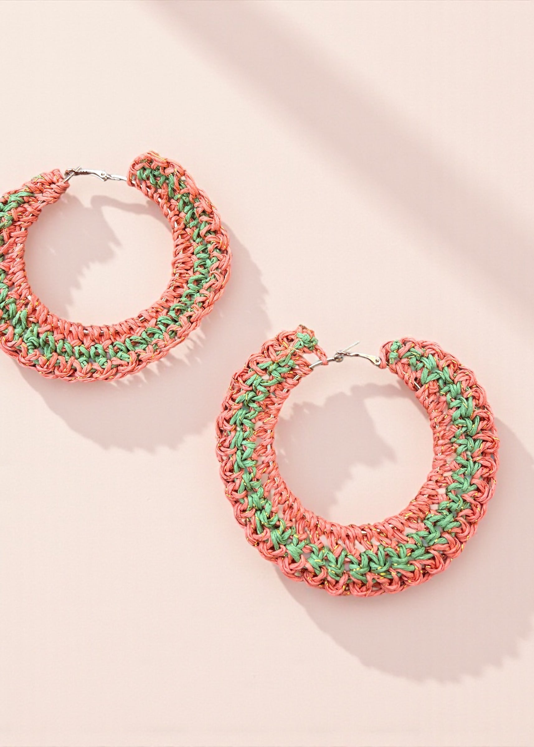 Coral and green crochet hoop earrings by ThatRomeo on a soft pink background.