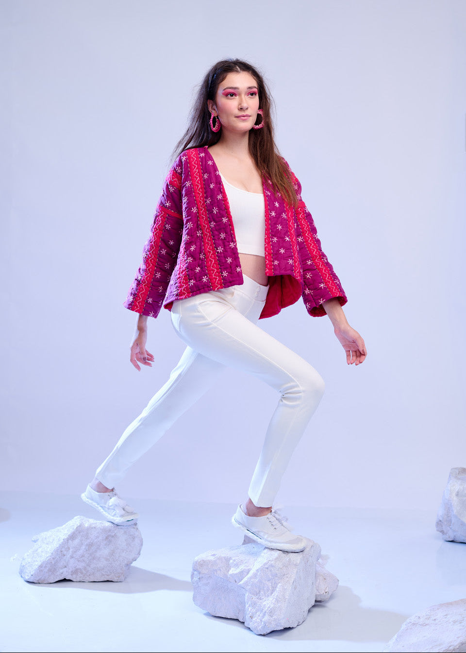 Model wearing ThatRomeo’s Fuchsia Bloom Quilted Jacket — bright fuchsia cotton jacket with white embroidery, styled with white pants.