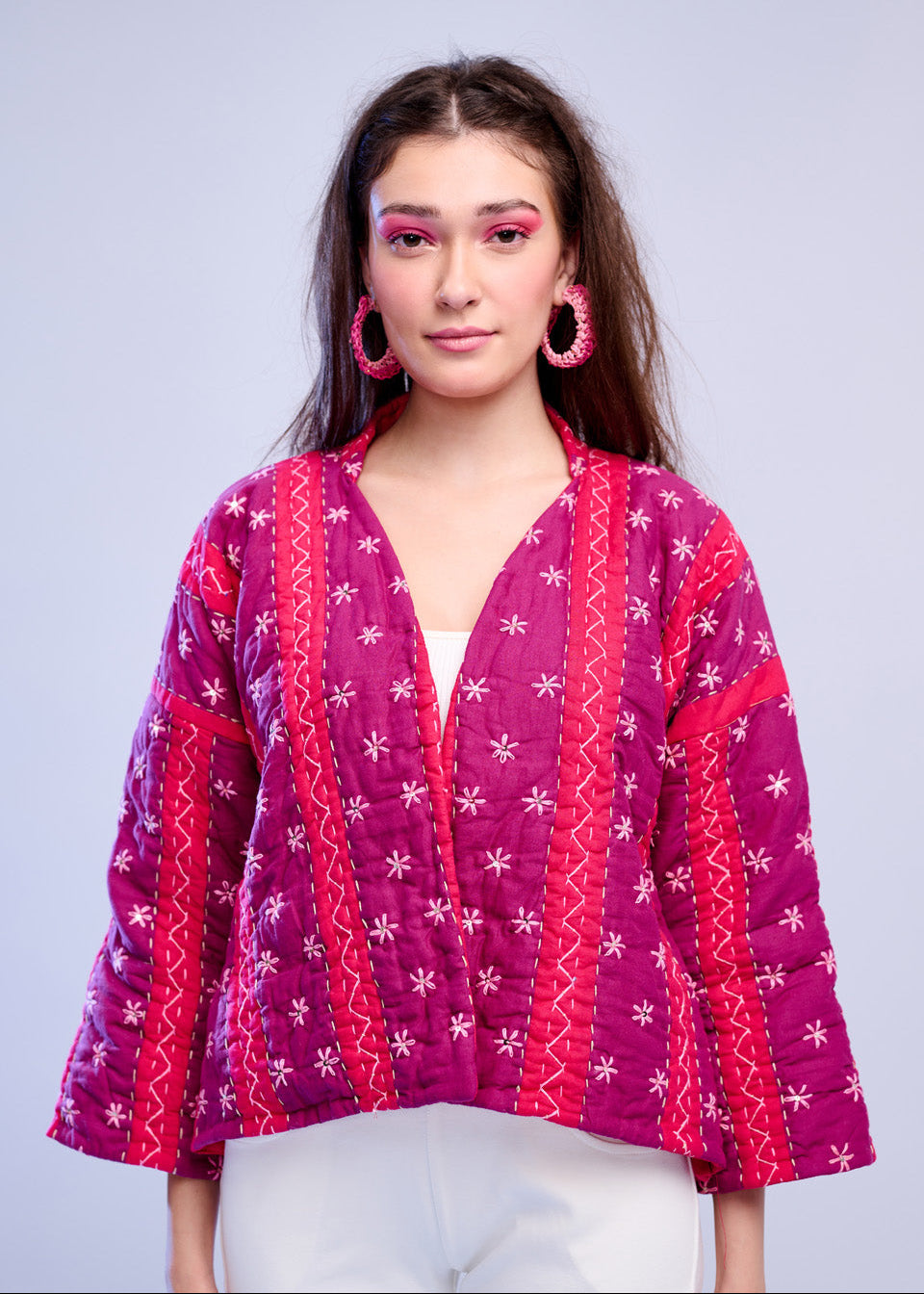 Model wearing ThatRomeo’s Fuchsia Bloom Quilted Jacket — bright fuchsia cotton jacket with white embroidery, styled with white pants.