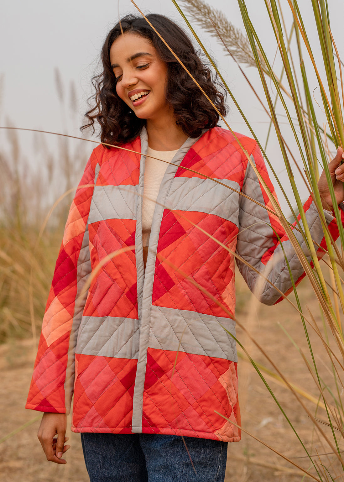 Model wearing ThatRomeo’s Maple Squarzy Patchwork Jacket — grey and red geometric quilted jacket in longline silhouette.