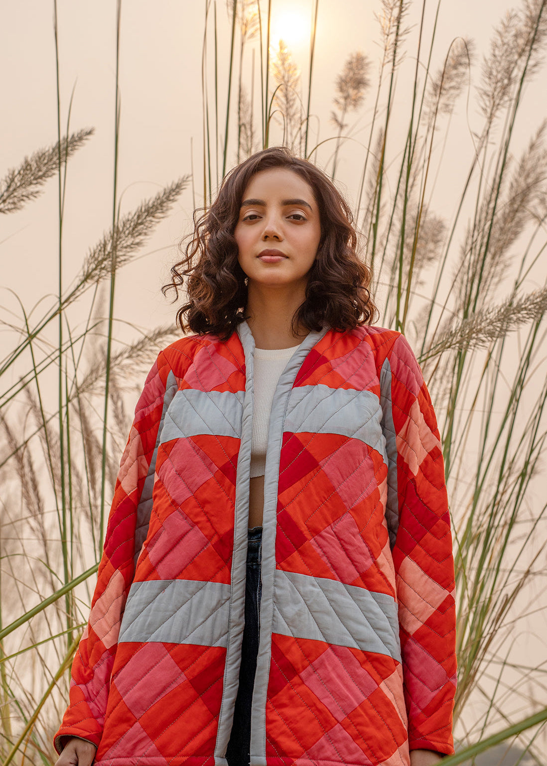 Model wearing ThatRomeo’s Maple Squarzy Patchwork Jacket — grey and red geometric quilted jacket in longline silhouette.