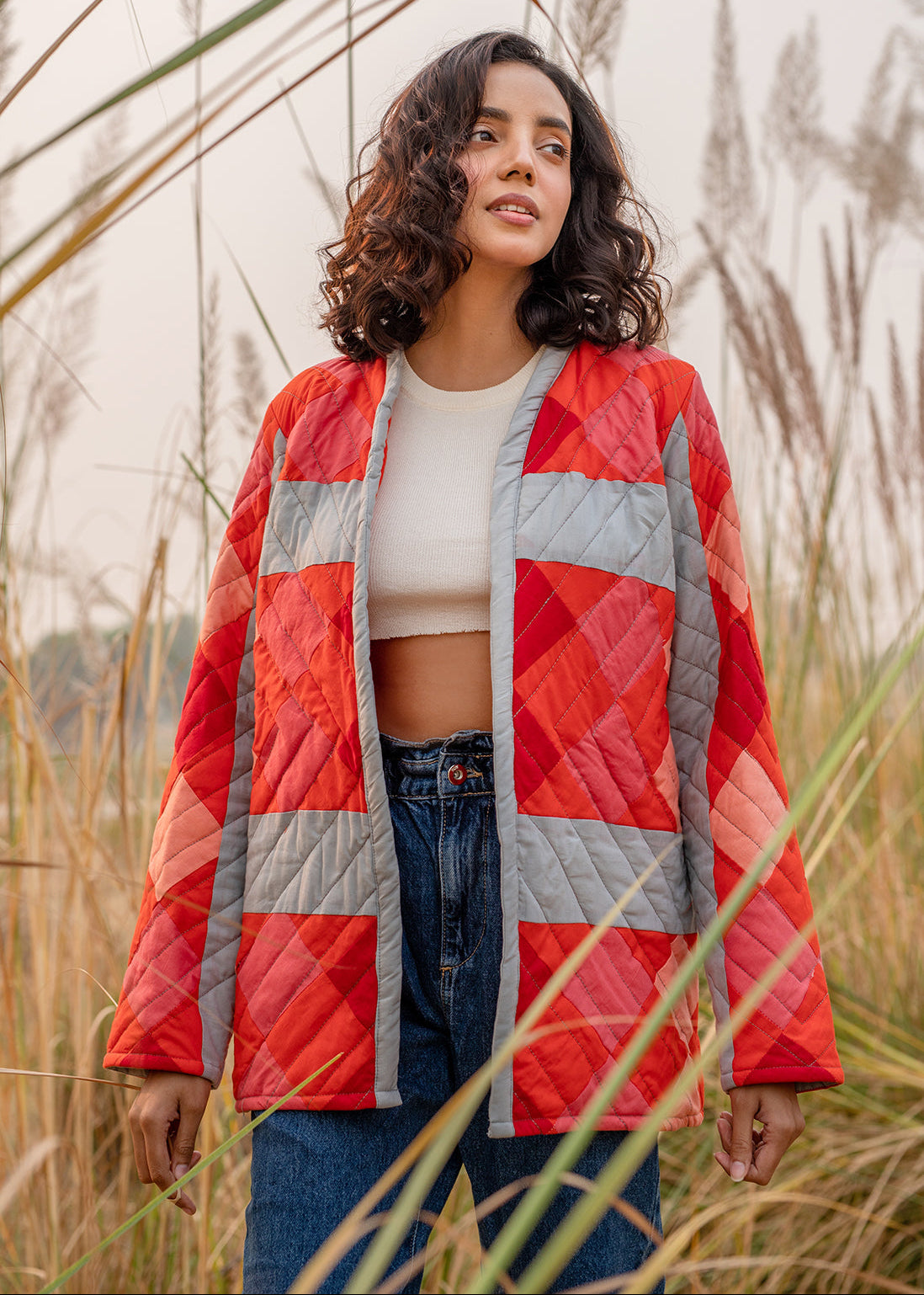 Model wearing ThatRomeo’s Maple Squarzy Patchwork Jacket — grey and red geometric quilted jacket in longline silhouette.