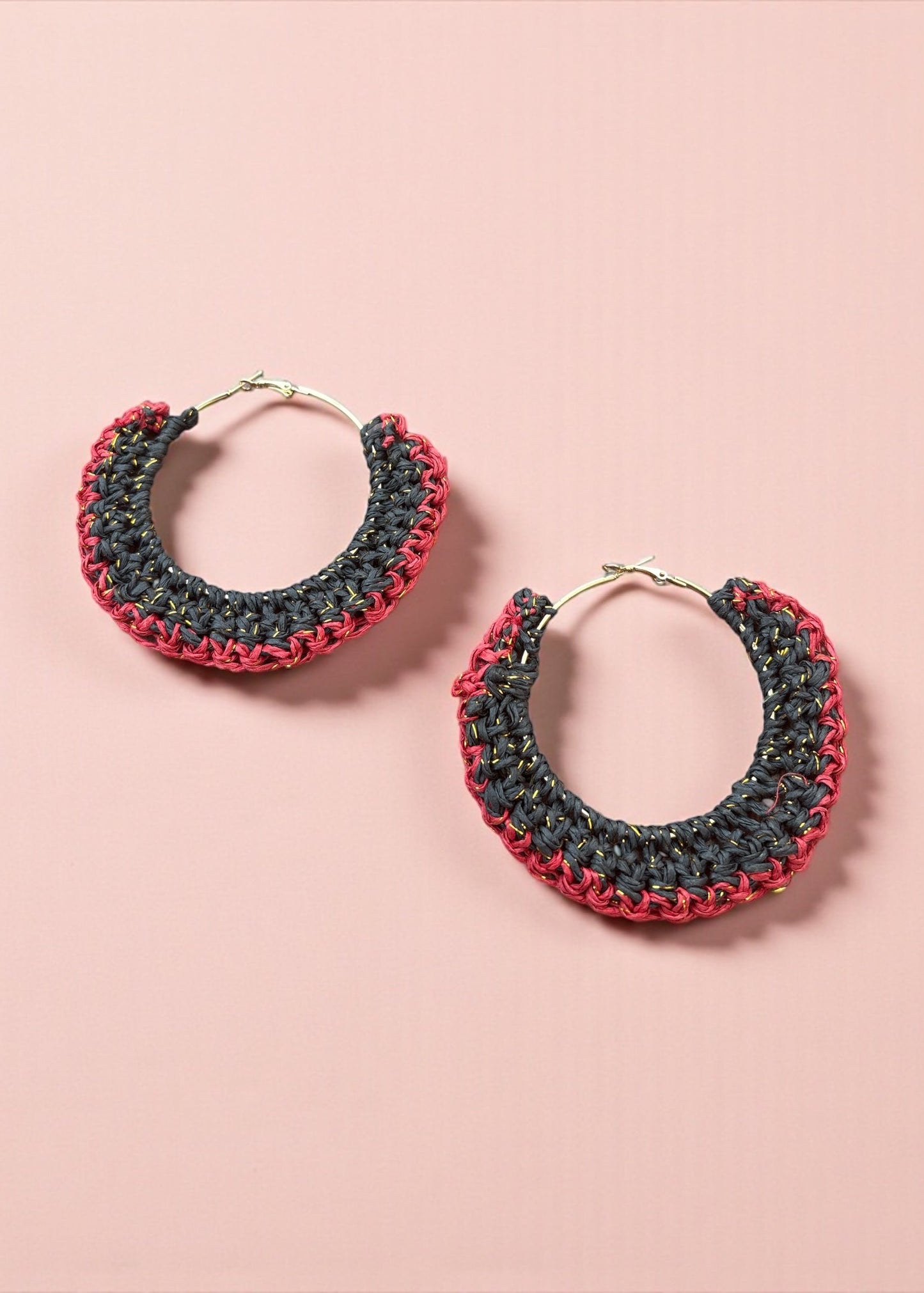 Charcoal black and red crochet hoop earrings by ThatRomeo on a blush background.
