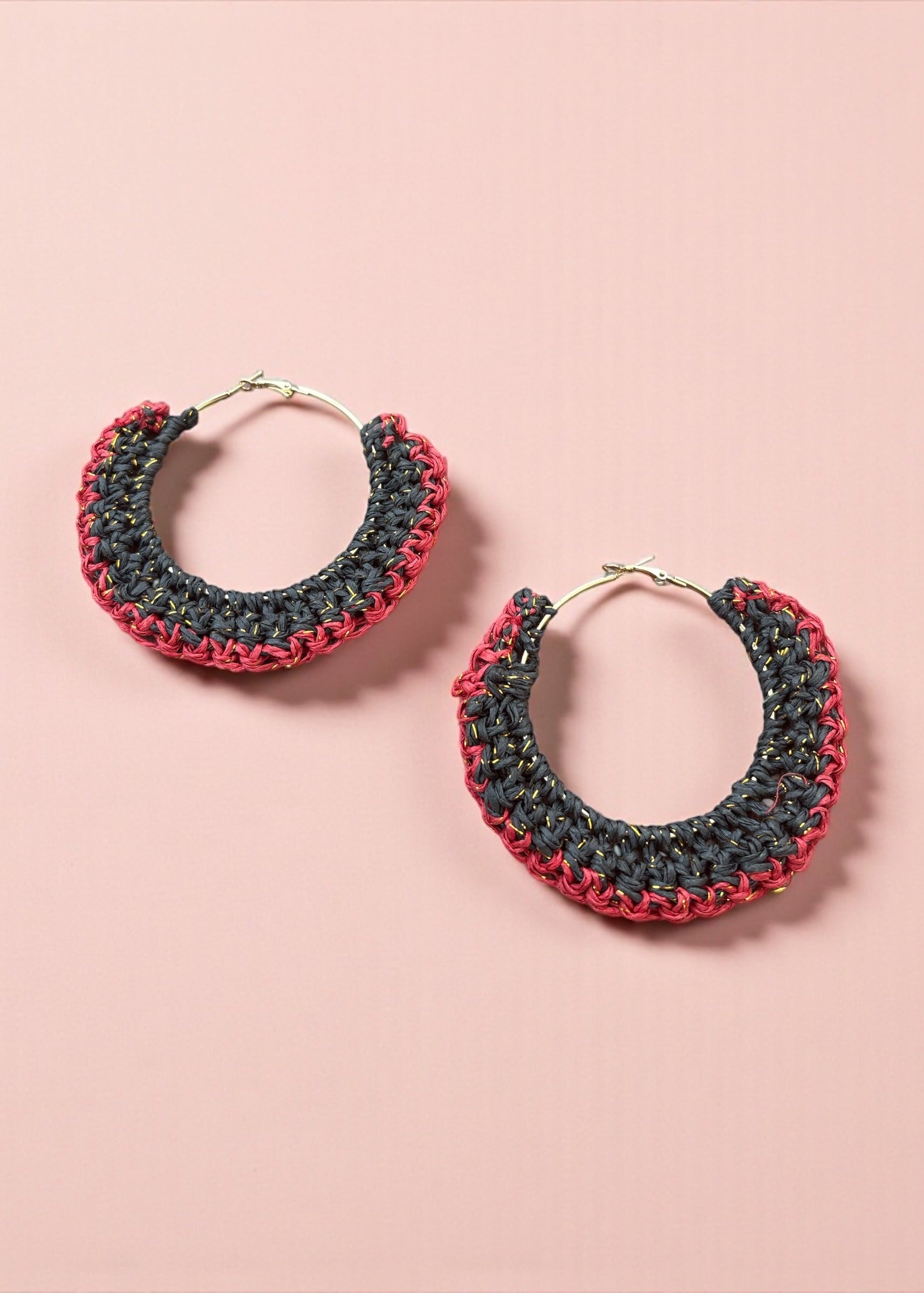 Charcoal black and red crochet hoop earrings by ThatRomeo on a blush background.
