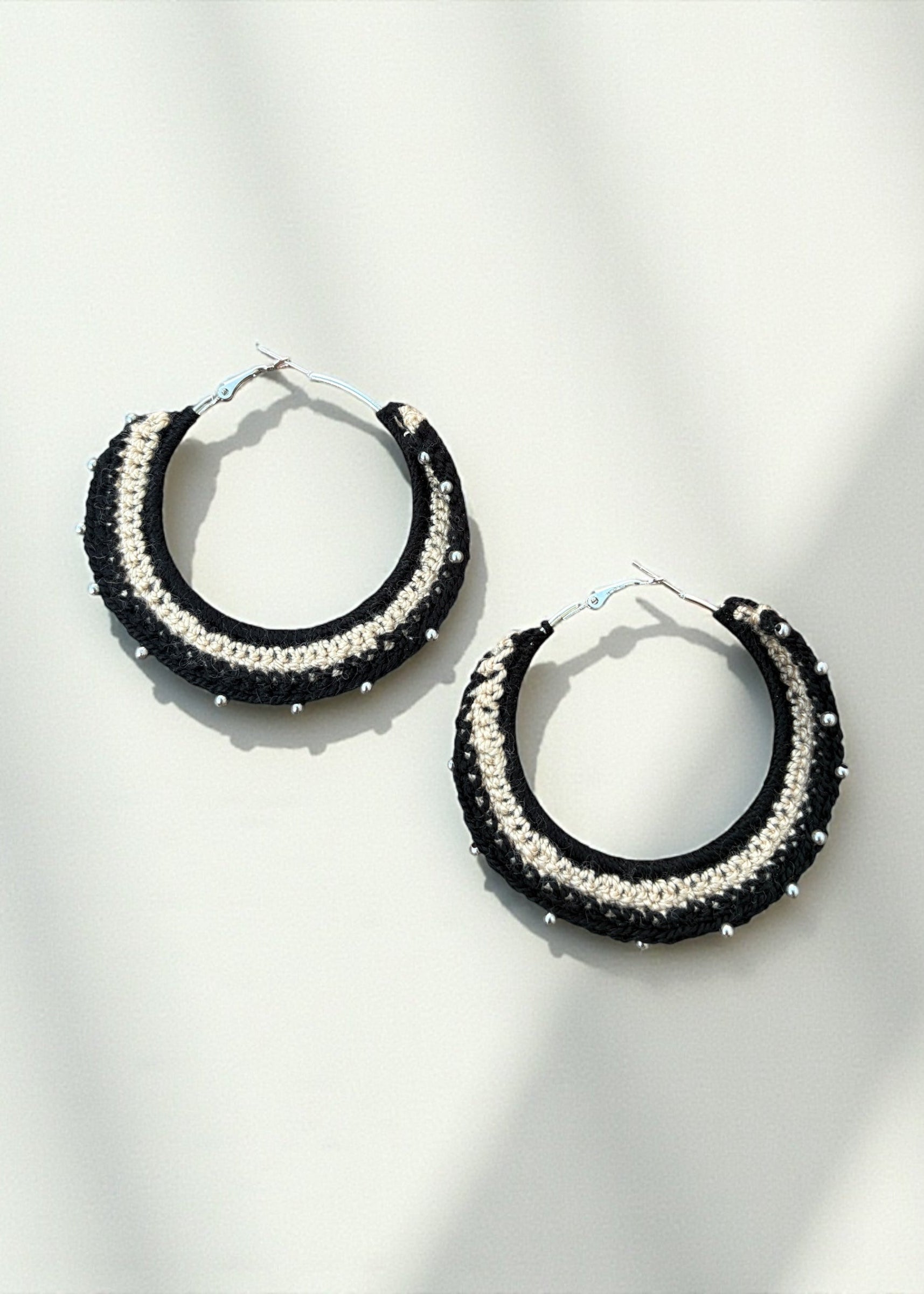Black and cream crochet hoop earrings with bead accents by ThatRomeo on a soft-light background.