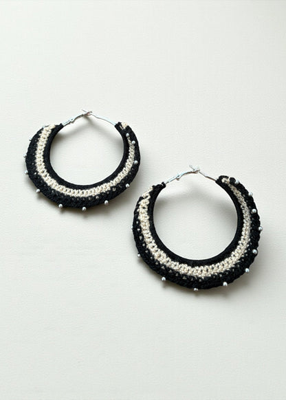 Black and cream crochet hoop earrings with bead accents by ThatRomeo on a soft-light background.